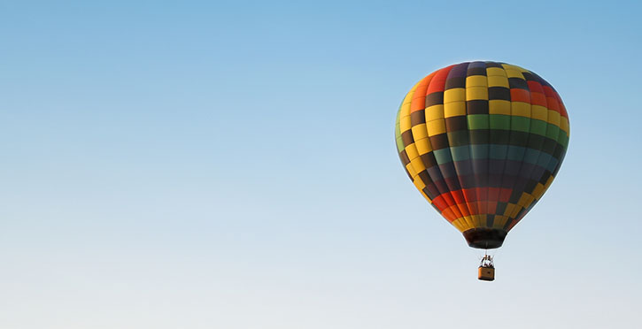 Hot air baloon with colorful square pattern rising in the air