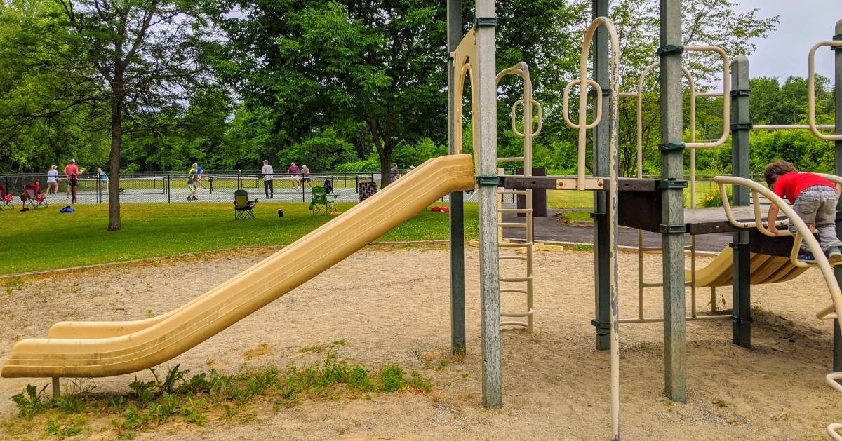 kid on playground, people playing pickleball in the background