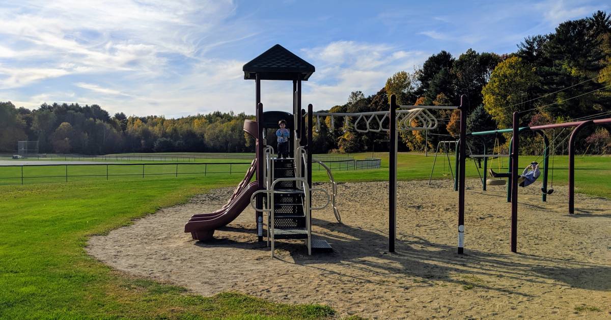 a kid on a playground, someone on swings