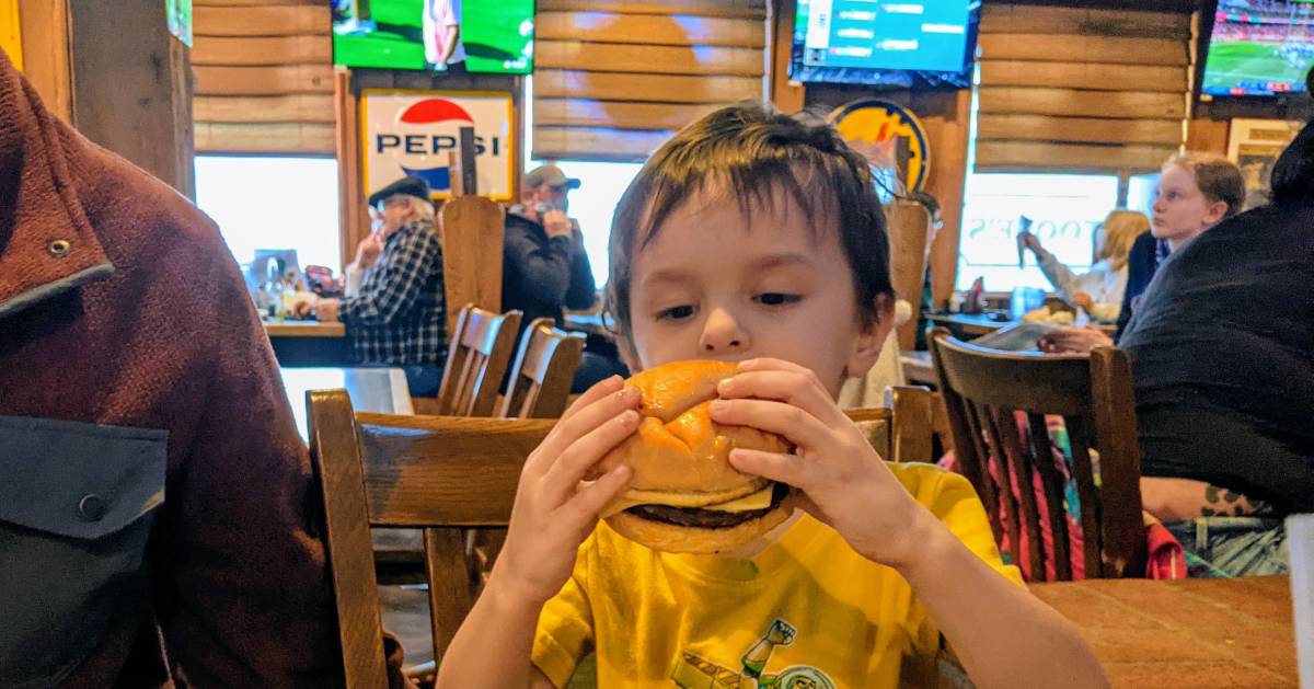 kid in restaurant with a cheeseburger