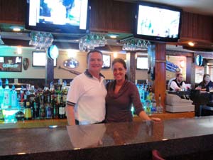 Man and woman posing behind bar