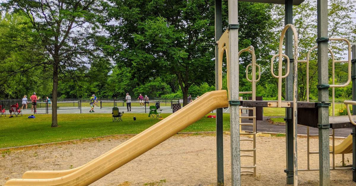 playground with people playing pickleball in the background