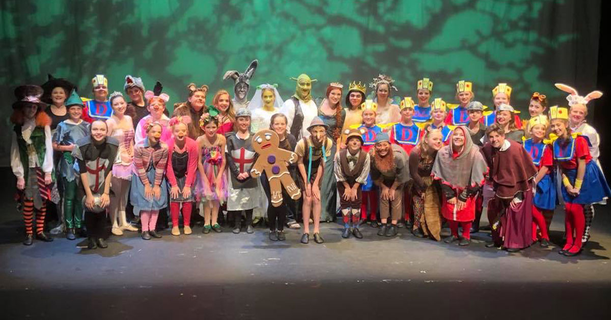 a large theater cast posing on stage